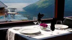 Mesa lista para comer con vista a un paisaje montañoso y un cuerpo de agua.