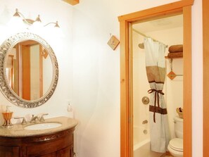 Un baño con espejo redondo, lavabo y cortina de ducha.