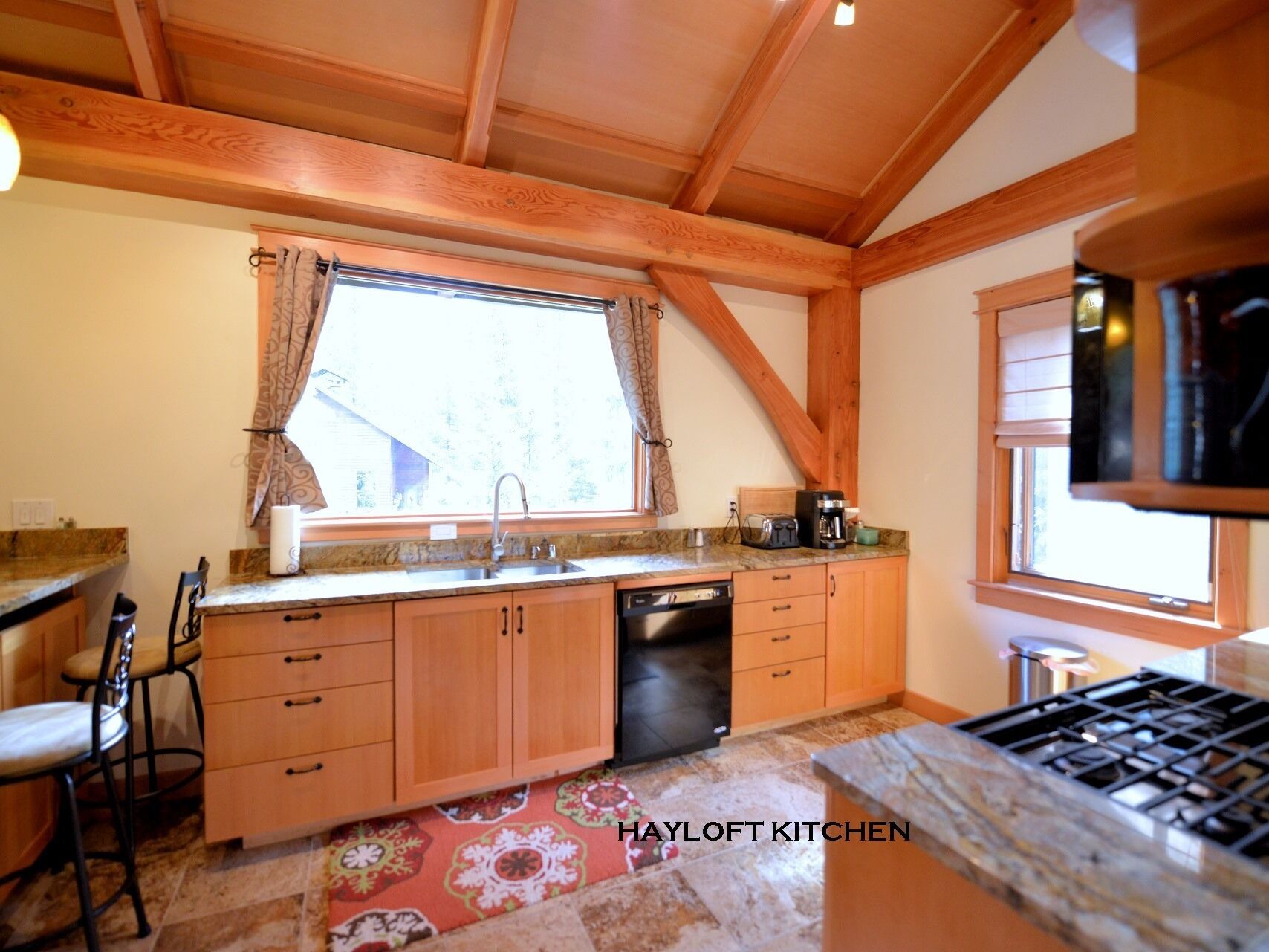 A kitchen with wooden cabinets, a built-in dishwasher, a window with curtains, and a stove.