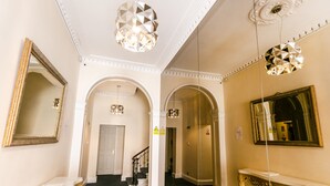 A spacious hallway with a grand staircase, ornate mirrors, and elegant lighting fixtures. - Park Lane Apartments - Clarges St (London)