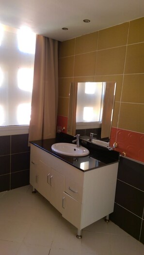 A bathroom with a white sink, a mirror, and a cabinet with drawers. - Al Dora Residence (Hurghada)