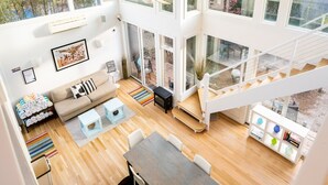 A spacious, modern interior with a large dining area, a cozy seating area, and a staircase leading to an upper level.