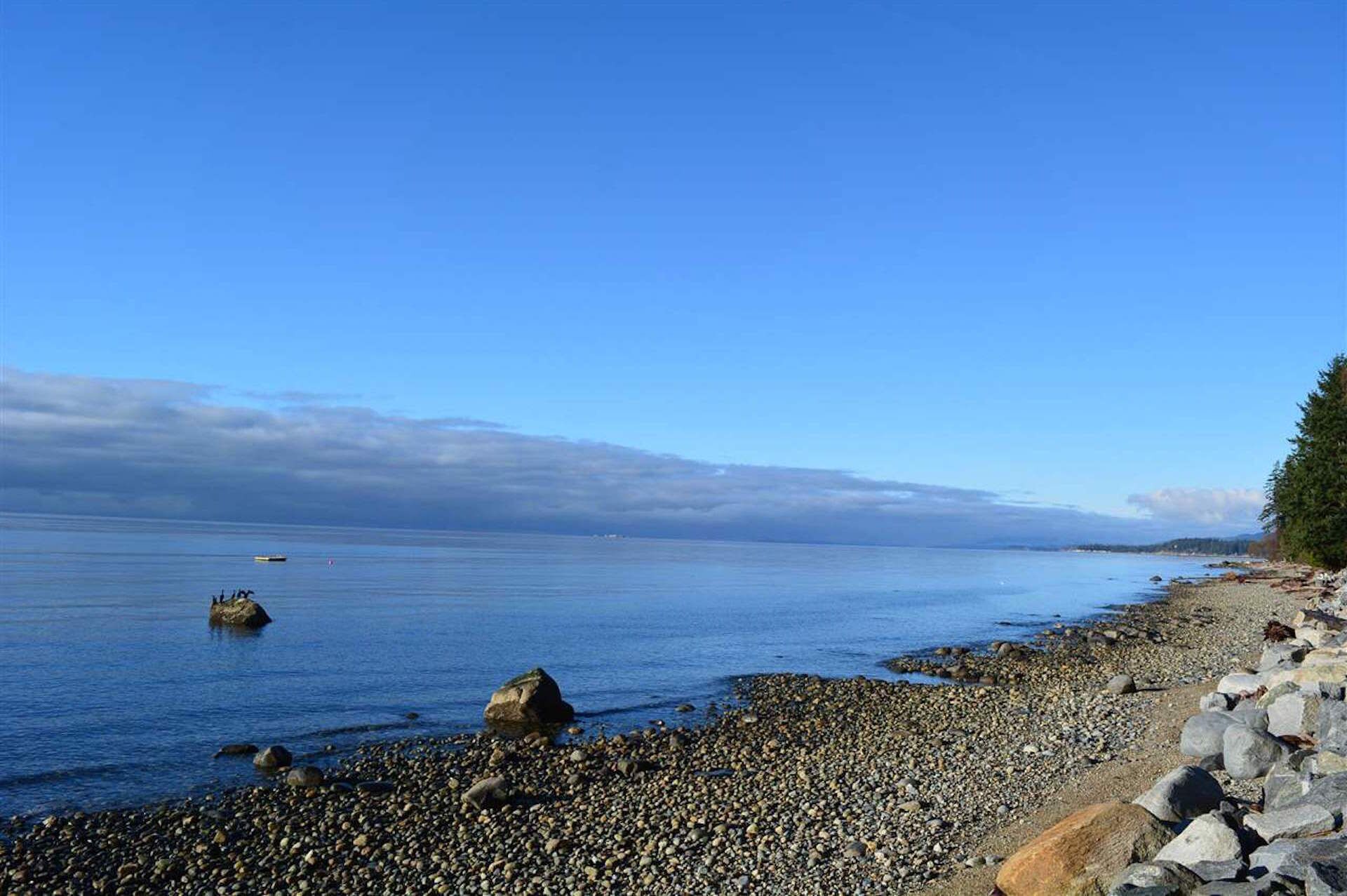 A rocky shoreline with a clear view of the ocean and distant land.
