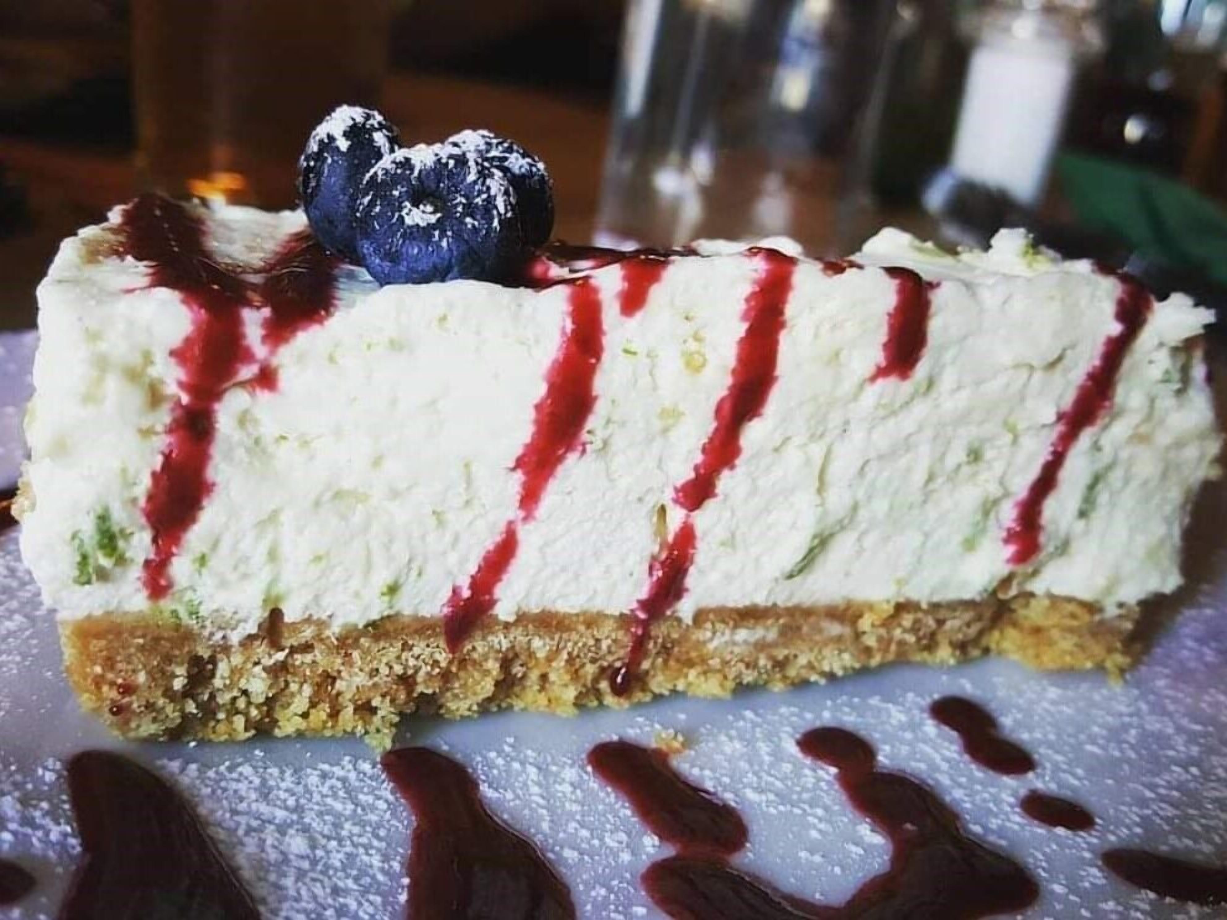 A slice of cheesecake with a berry compote and a blueberry on top.