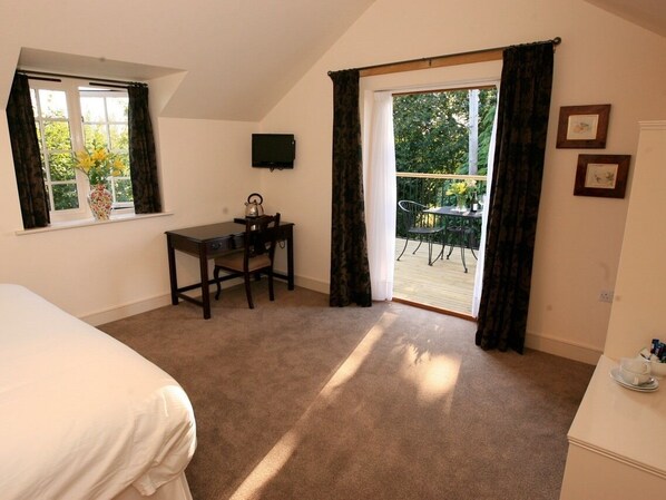 A bedroom with a bed, a desk, a chair, a television, and a balcony with a table and chairs. - The Oak Inn Staplow (Ledbury)