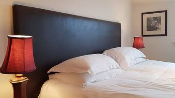 A hotel room with a large bed, two bedside lamps, and a framed picture on the wall.