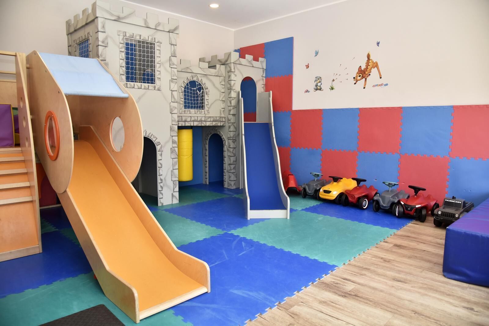 A play area with a slide, a castle play structure, and toy cars.