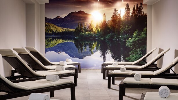 Un cuarto de spa con sillones reclinables y un gran mural de un lago de montaña al atardecer.