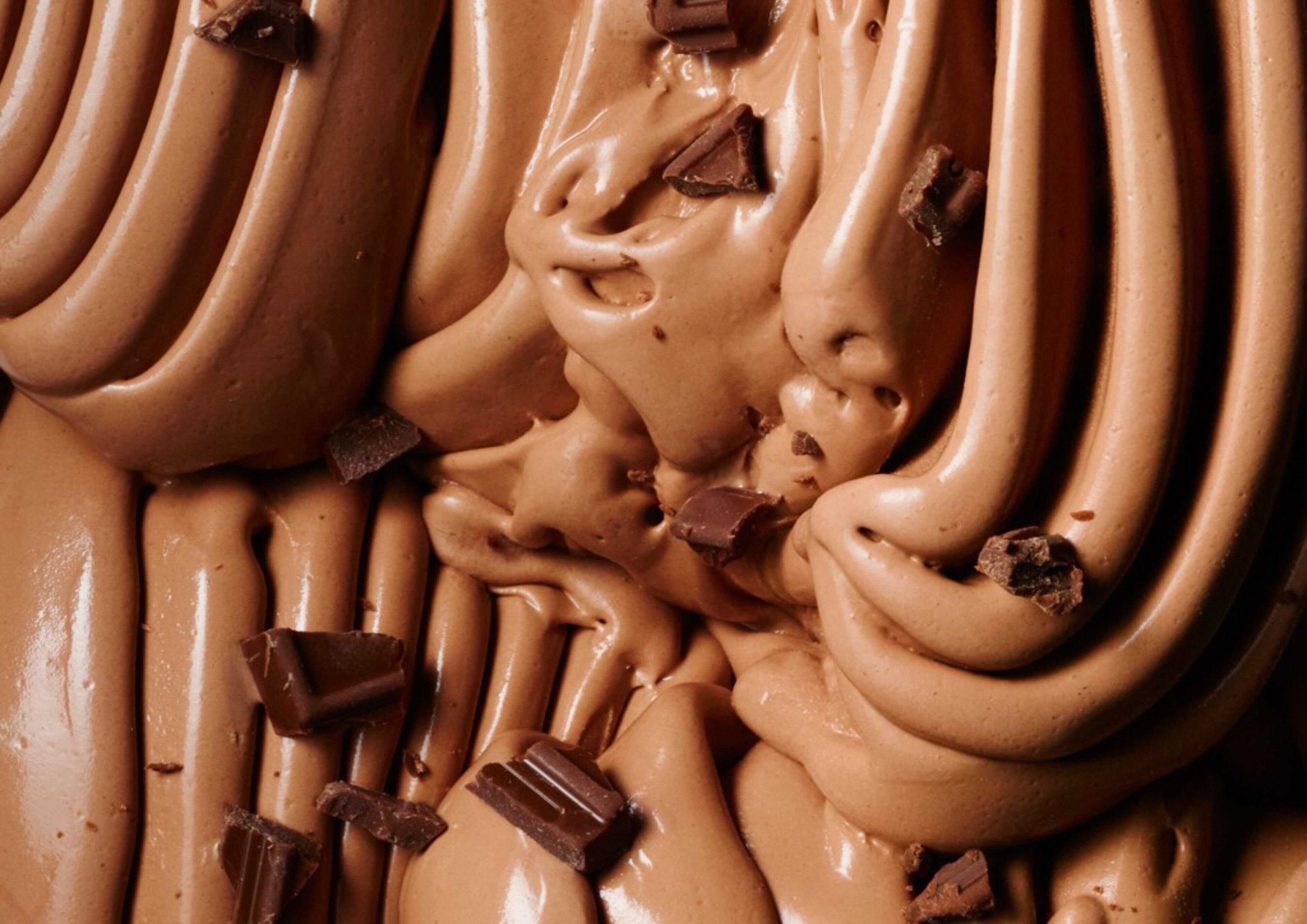 Primer plano de un postre cremoso con trozos de chocolate.