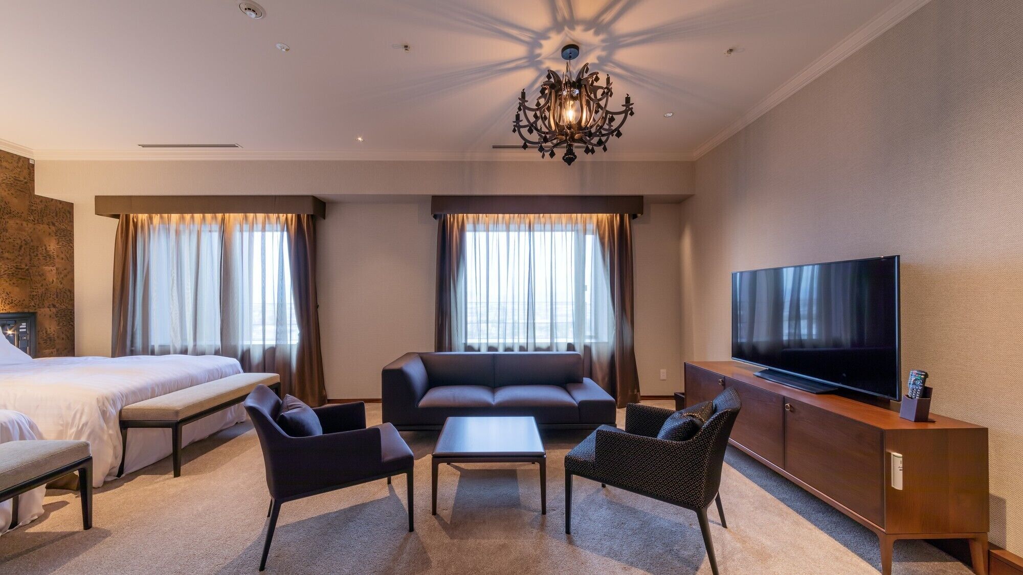 Una habitación de hotel con cama, sofá, televisor y candelabro.