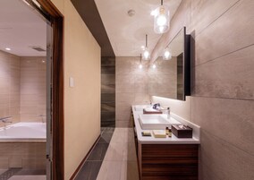 A modern bathroom with two sinks, a large mirror, and pendant lighting.