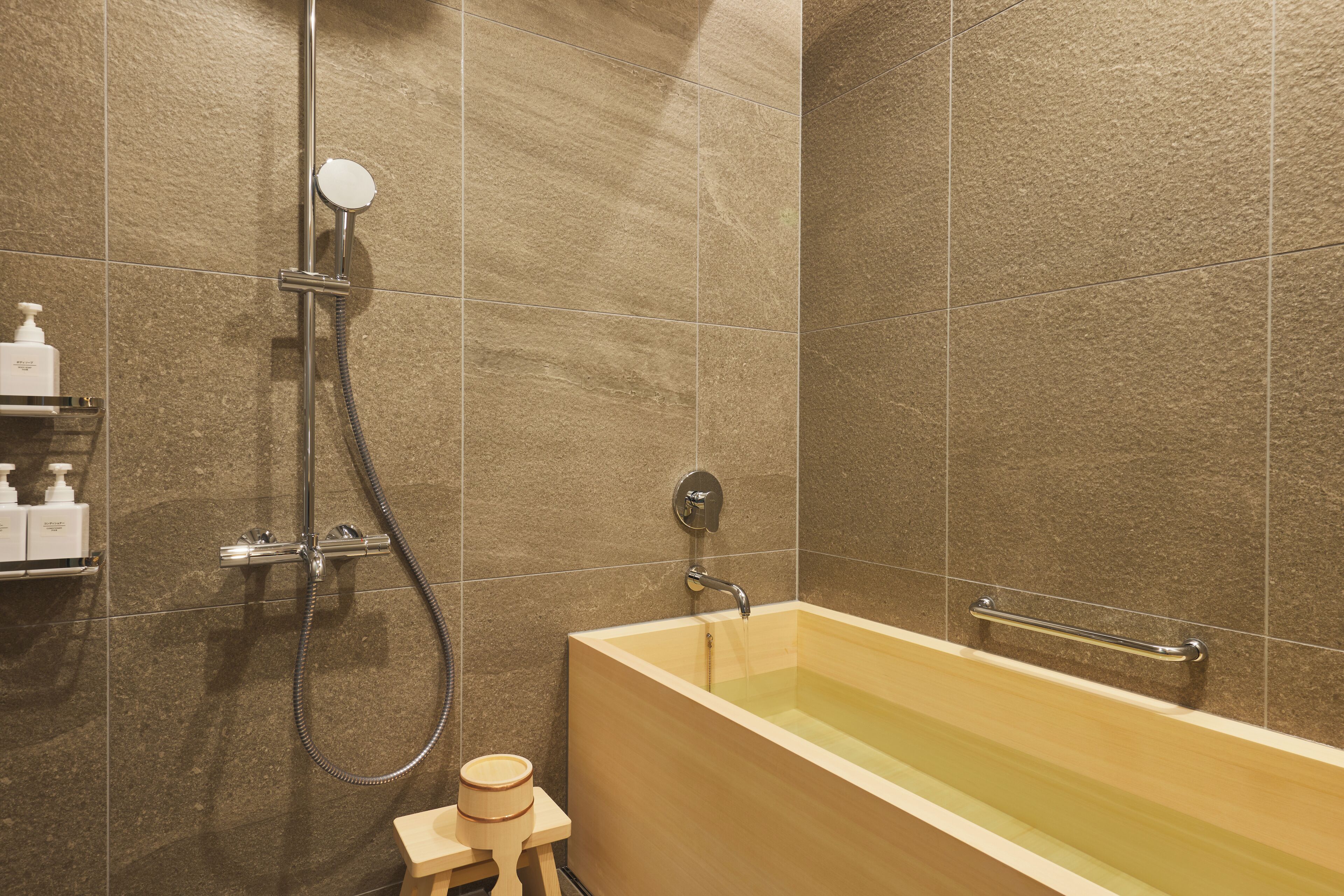 A modern bathroom with a bathtub, shower, and hand soap dispenser on a shelf.