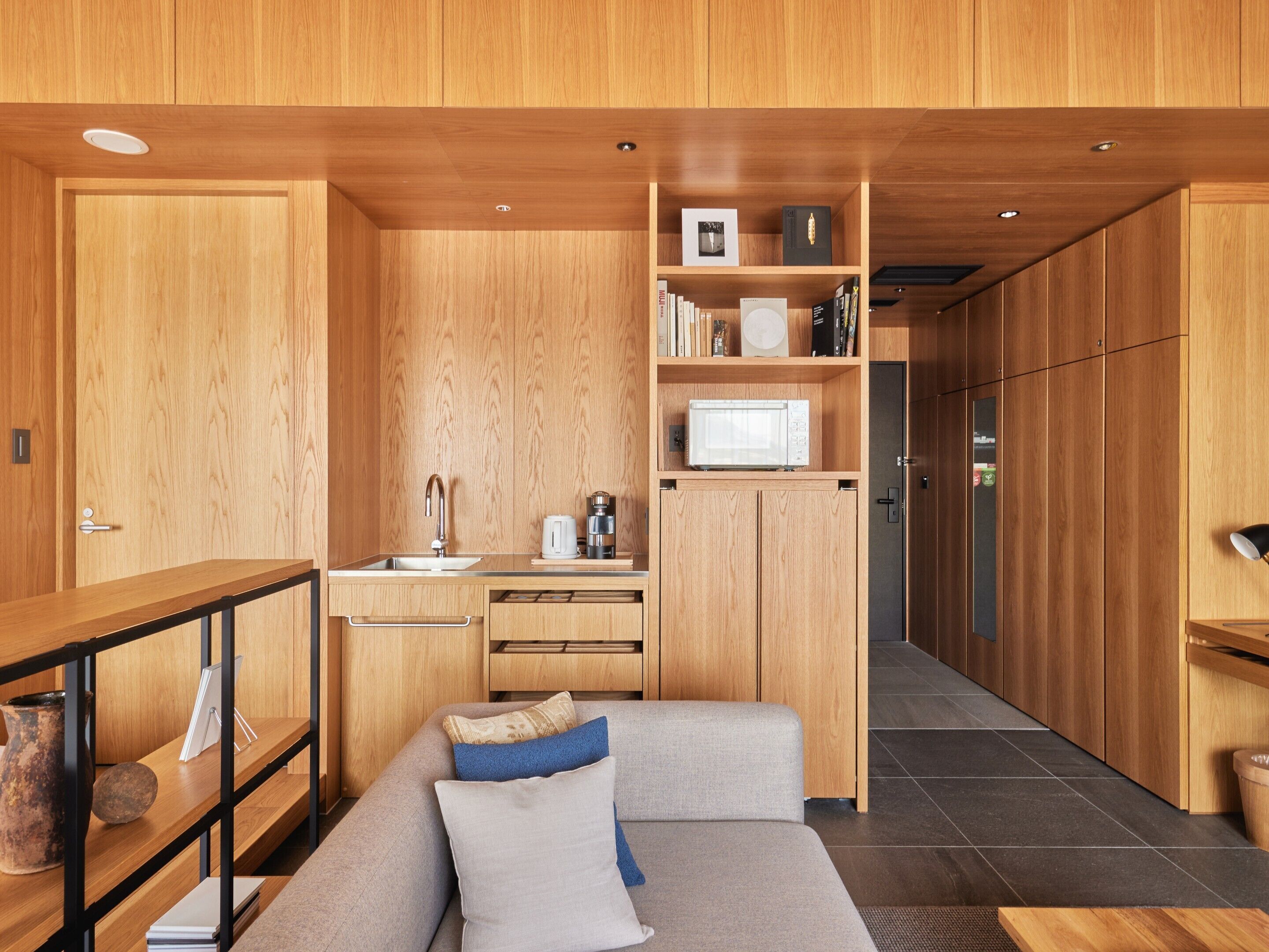 A modern kitchen with wooden cabinets, a built-in microwave, and a coffee machine.