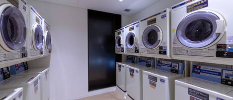 A laundry facility with multiple washing machines and dryers, arranged in rows.
