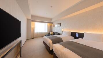 A hotel room with two beds, a flat-screen TV, a large window, and a wall-mounted control panel.