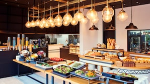 Een buffetopstelling met diverse gerechten en een moderne keuken op de achtergrond.