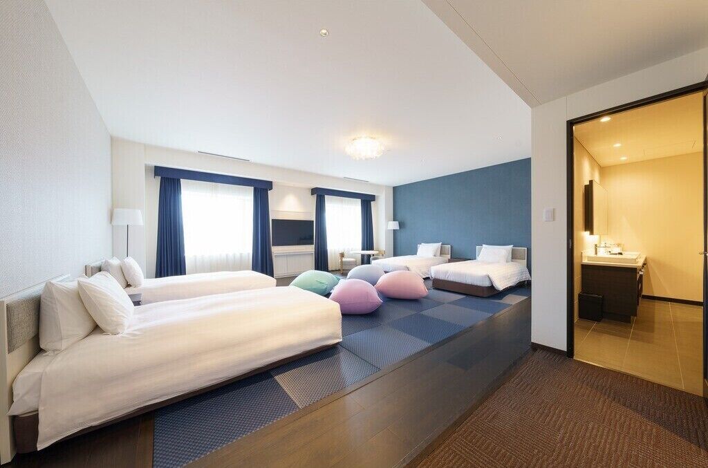 A hotel room with two beds, a bathroom, and a view of the city.