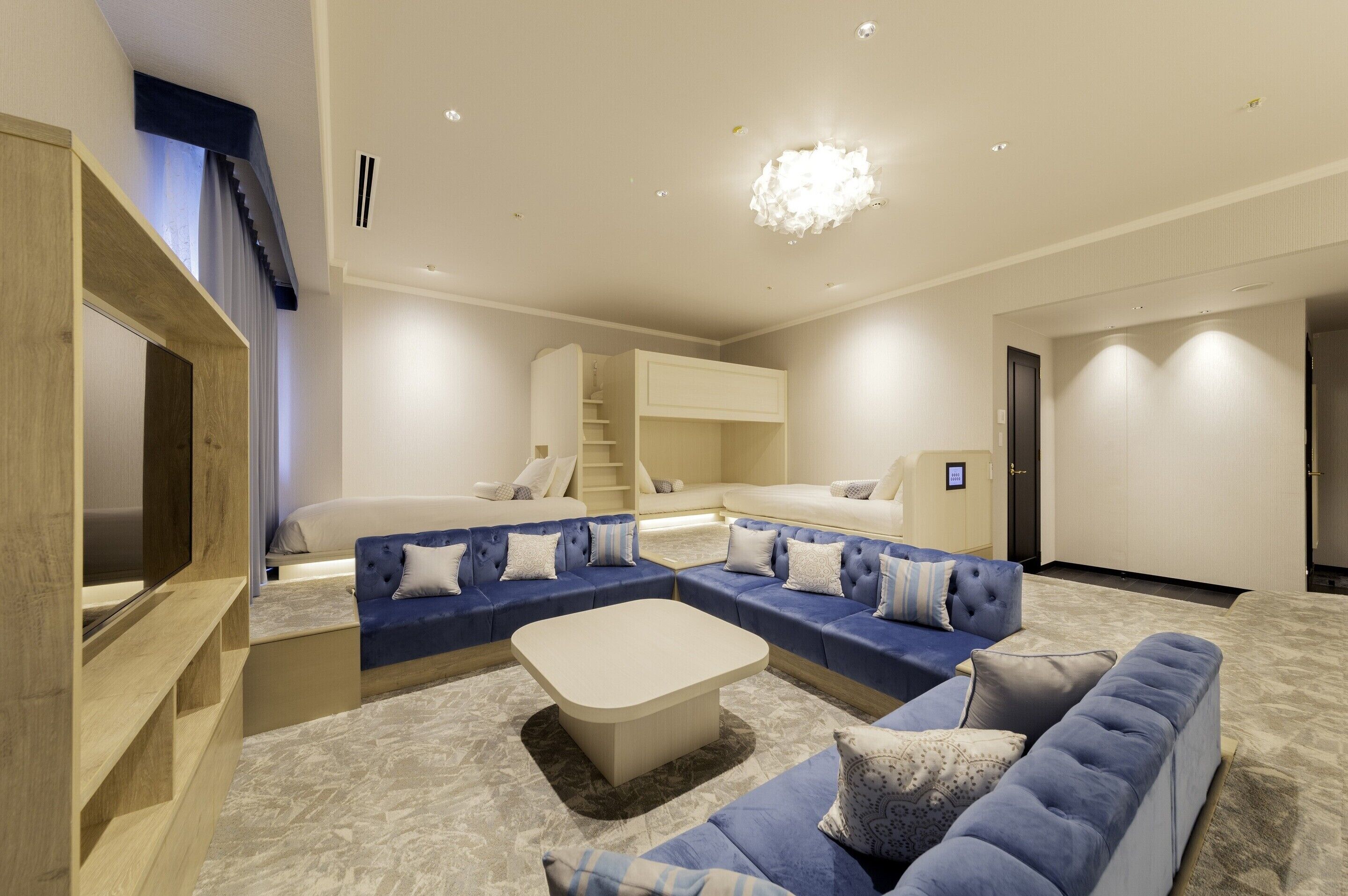 A modern living room with a sectional sofa, a flat-screen TV, and a staircase leading to a loft bedroom.