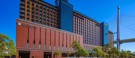 A modern hotel with a prominent red brick facade and a glass tower.