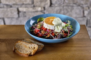 A bowl of salad with a piece of bread on a wooden table. - Hotel Pecr Deep (Pec pod Snezkou)