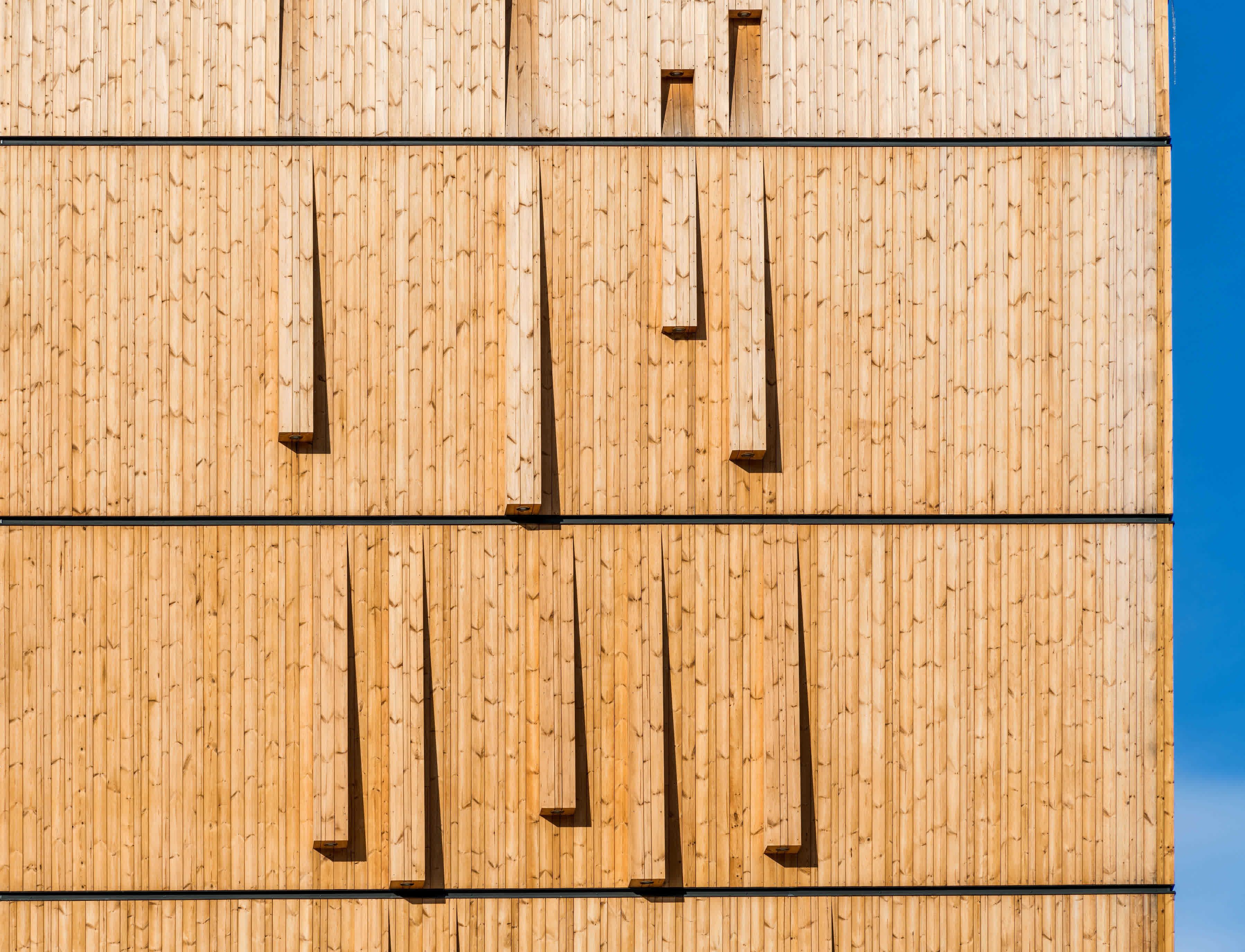 A wooden wall with vertical planks and rectangular cutouts.