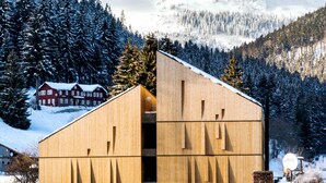 A wooden building with a sloped roof, surrounded by snow-covered trees and mountains. - Hotel Pecr Deep (Pec pod Snezkou)