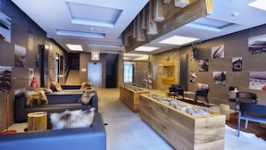 A modern interior with a sofa, wooden reception desk, and a stone wall. - Hotel Pecr Deep (Pec pod Snezkou)