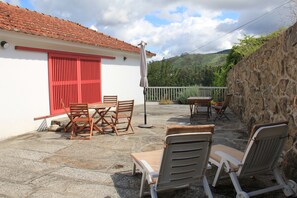 Une terrasse avec des meubles d’extérieur, une table et des chaises.
