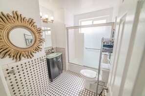 Une salle de bain avec un miroir en forme de soleil, un lavabo, des toilettes et un espace douche.