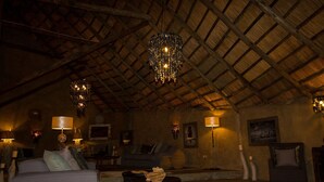 Un espace salon accueillant avec un toit de chaume, un canapé, une table basse et des lampes fixées au mur.