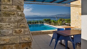 A stone wall, a pool, and a view of the sea. - Villa Violet (Supetar)