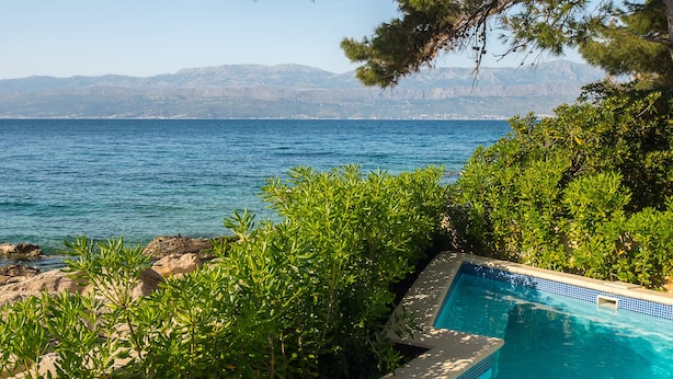 Ein Schwimmbad mit Blick auf das Meer und Berge im Hintergrund.