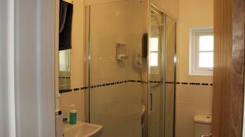 Un bagno con cabina doccia in vetro, lavabo con dispenser di sapone e WC.
