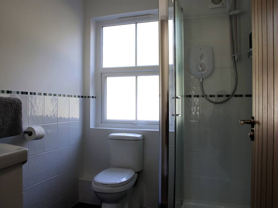 A bathroom with a toilet, a window, and a glass-enclosed shower.
