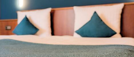 A bed with a blue blanket, a wooden headboard, and two pillows.