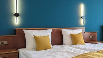 Una camera d'albergo con un letto, comodini e illuminazione a parete.