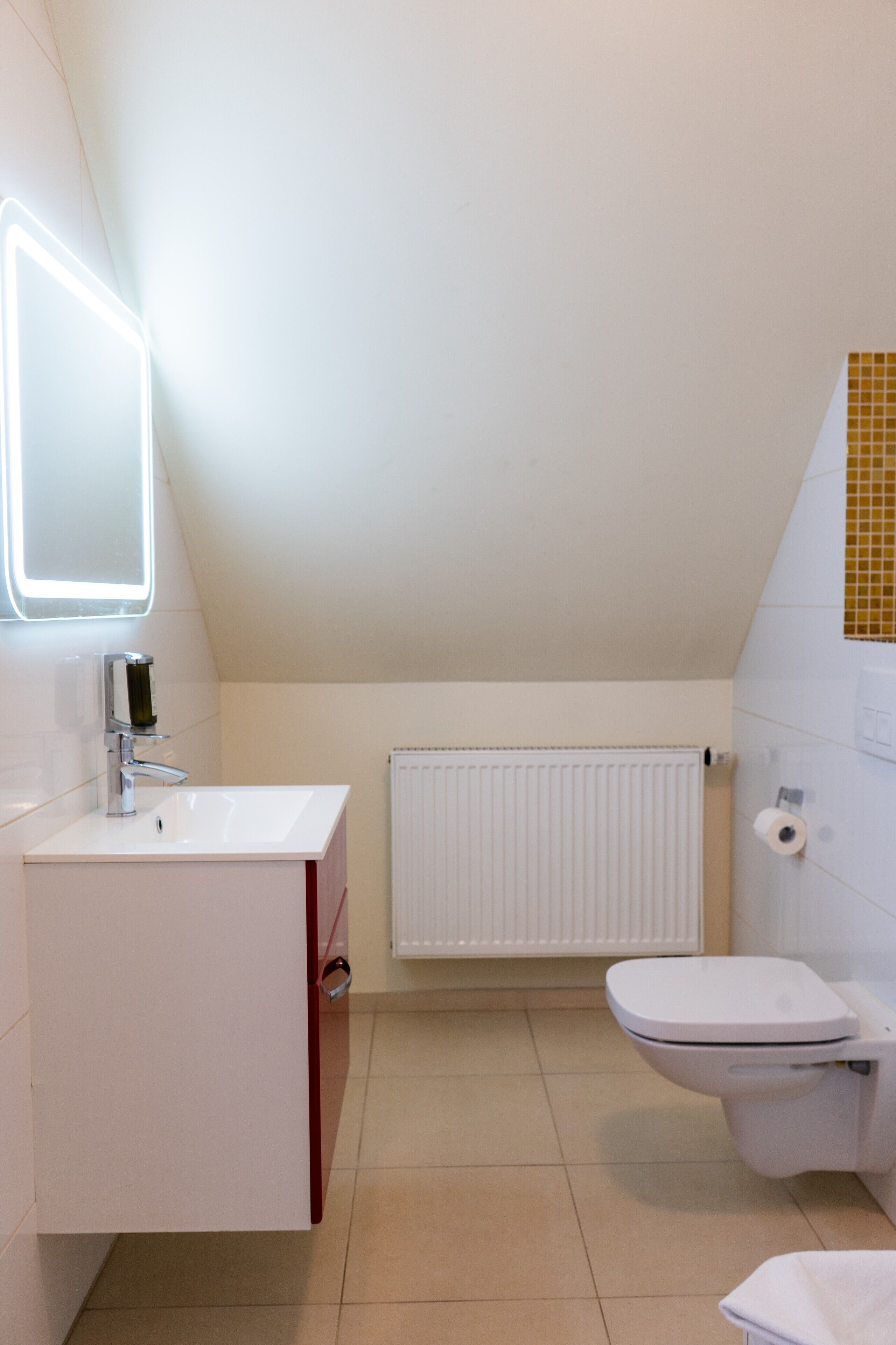 Un bany modern amb un rentapans blanc, un vàter i un radiador.