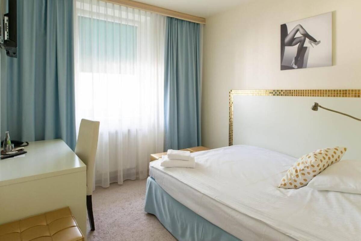 Una habitación de hotel con una cama, un escritorio y una silla.
