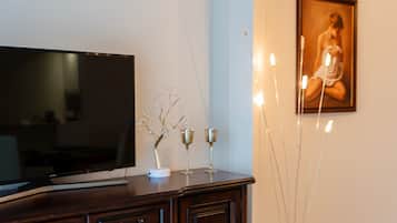Una sala de estar con un televisor de pantalla plana sobre un mueble de madera, aire acondicionado instalado en la pared y un cuadro enmarcado.