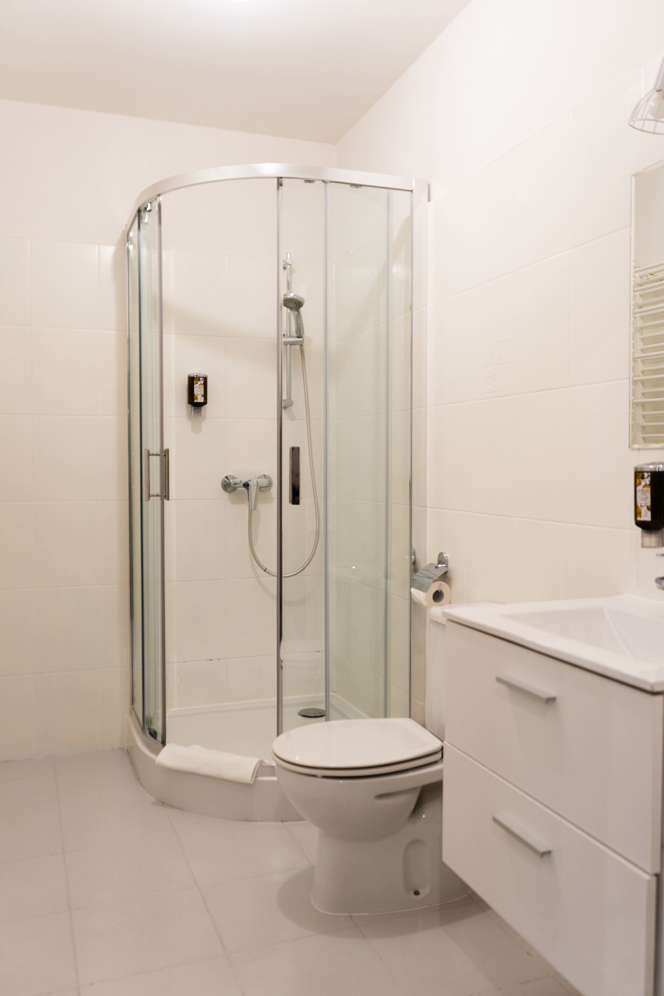 A modern bathroom with a glass-enclosed shower, a white toilet, and a white sink with a mirror above it.