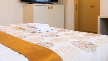 A hotel room with a bed, a television mounted on the wall, and a wardrobe.