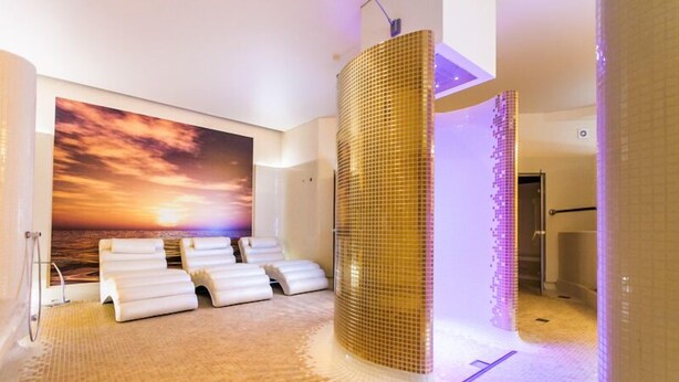 Un cuarto de spa con un mural al atardecer, piso con calefacción y un column grande y texturizado.