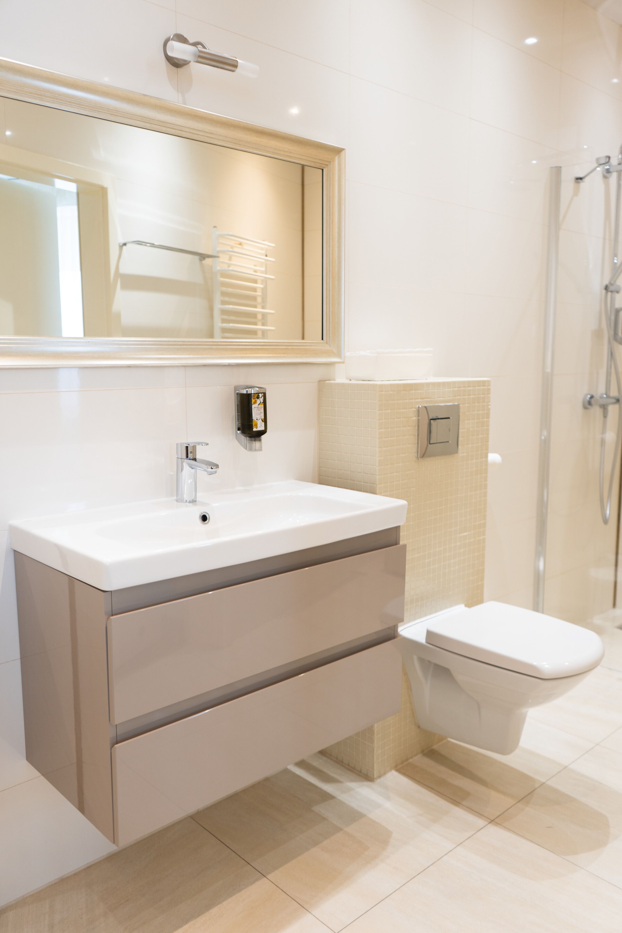 Un baño moderno con lavamanos blanco, espejo, inodoro y zona de ducha.