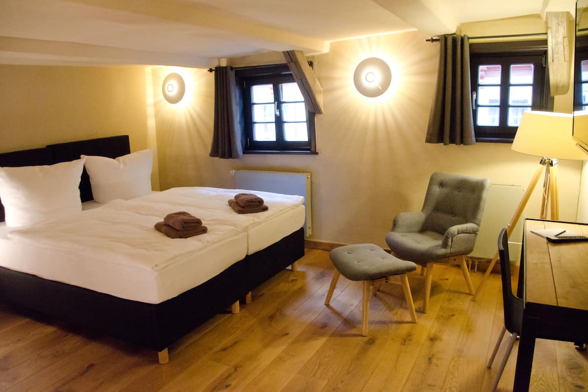 Ein Hotelzimmer mit Bett, Stuhl, Schreibtisch und Fenster.