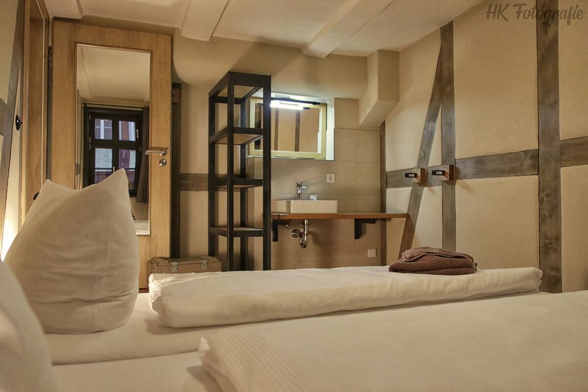 Ein Hotelzimmer mit zwei Betten, einem Holzschrank, einem Spiegel und einem kleinen Waschbecken.