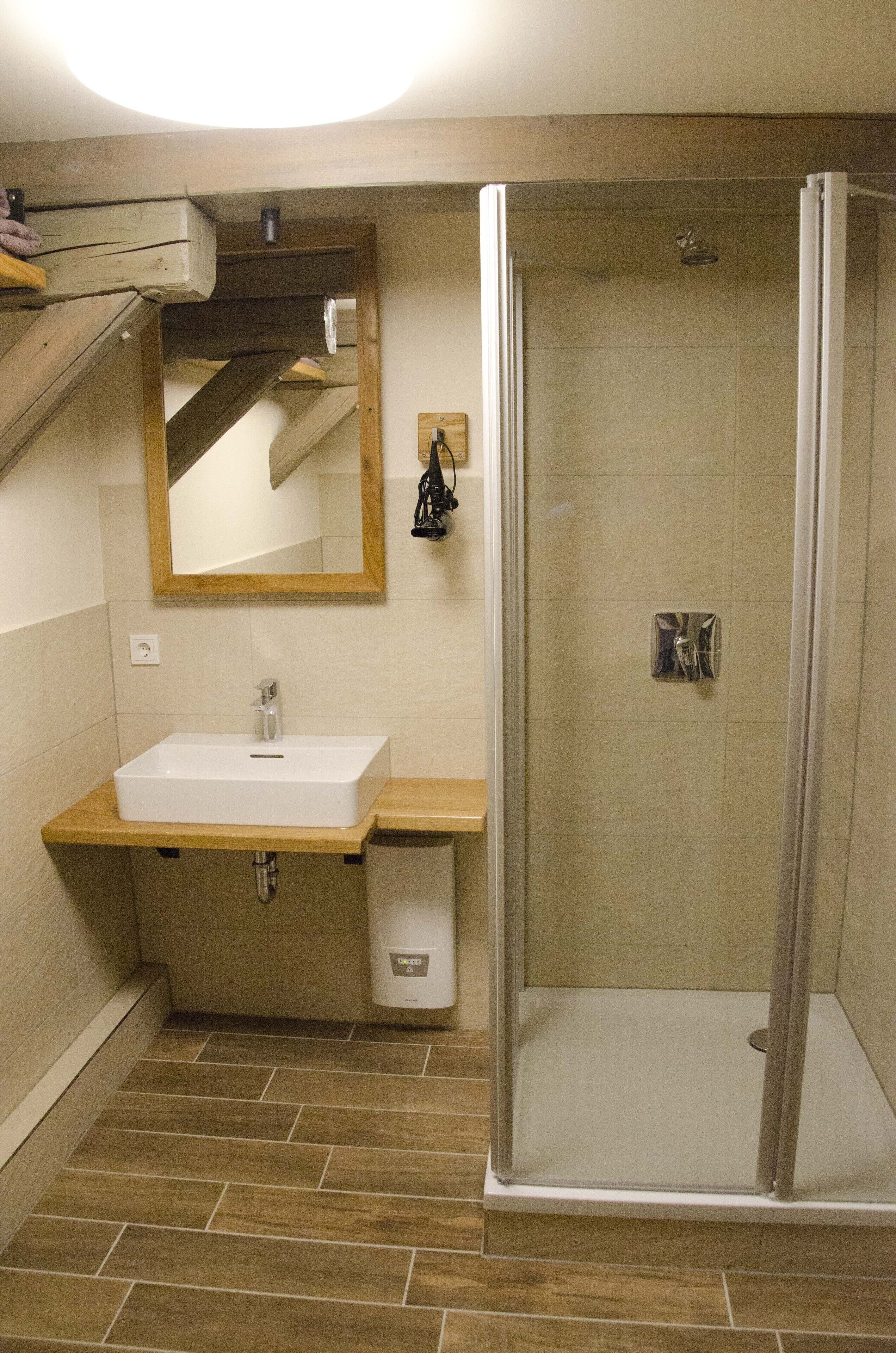 Un baño con lavamanos, espejo y ducha.