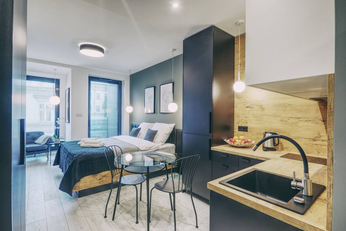 A modern bedroom with a bed, bedside table, and a small sitting area with a table and chairs.