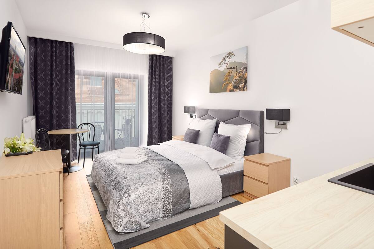 A modern bedroom with a bed, bedside tables, a desk, and a chair.