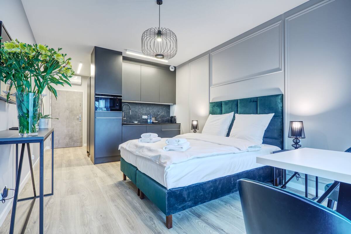 A modern hotel room with a bed, bedside table, and a small desk.