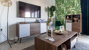 A modern living room with a flat-screen TV, wooden furniture, a plant, and a bookshelf. - Royal haneviim Boutique palace (Jerusalem)